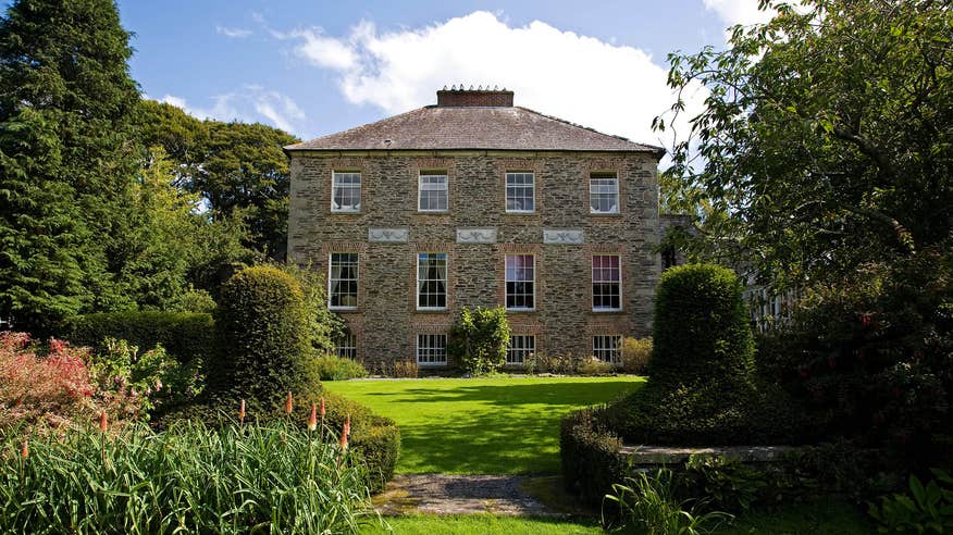 The exterior of a house at Kilmokea Country Manor Gardens with trees on either side.