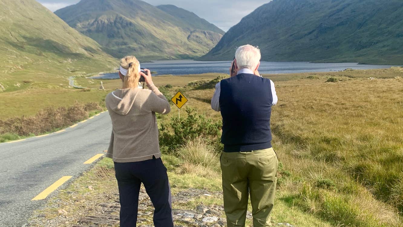 Two people taking photos of a lake