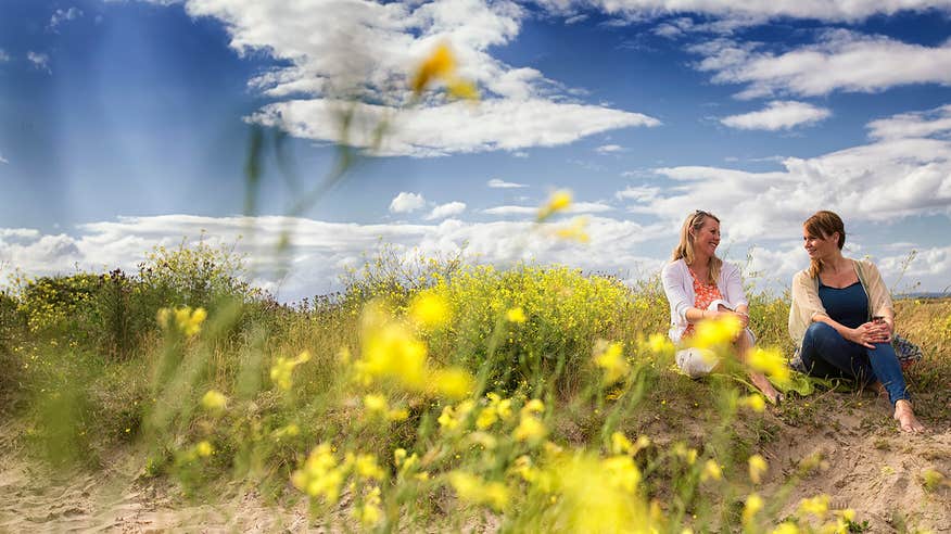 Two friends sitting beside flowers on Malahide Beach, Dublin