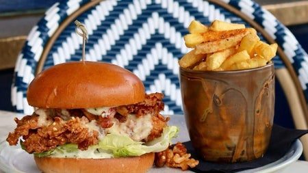 Crispy chicken burger served with lettuce and chips on a plate in an outdoor dining setting