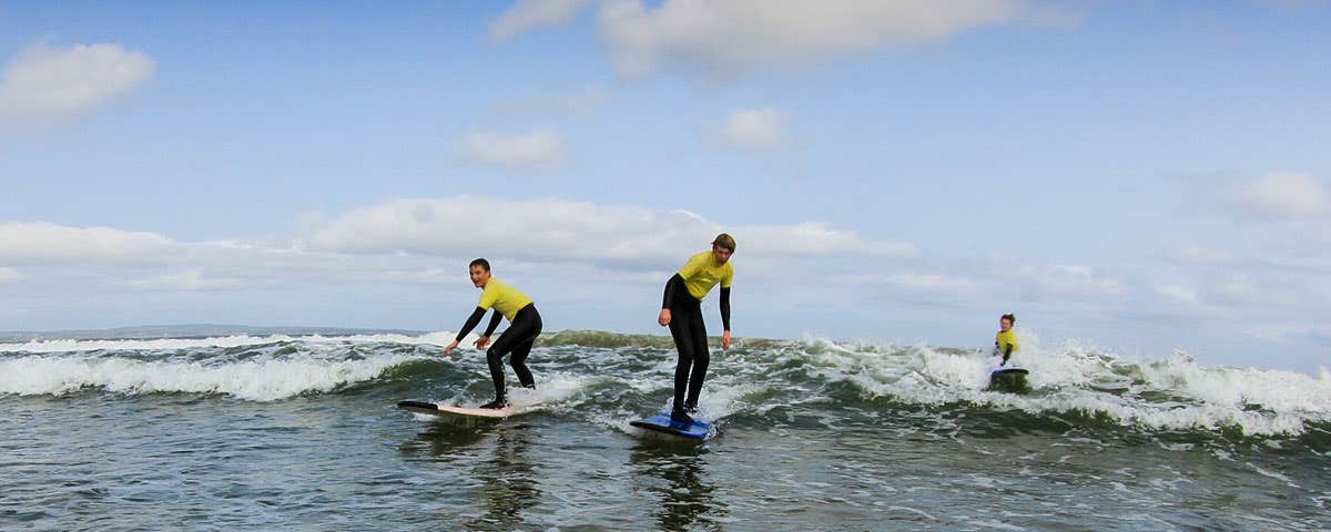 Three surfers on surfboards on the sea at a surf school in Sligo
