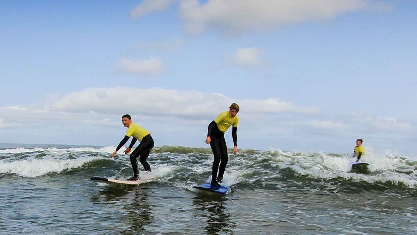 Three surfers on surfboards on the sea at a surf school in Sligo
