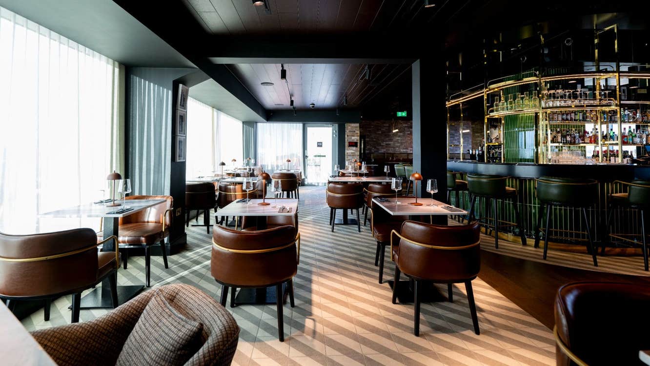 A bar and restaurant painted in dark colours with brown leather seating and floor tones