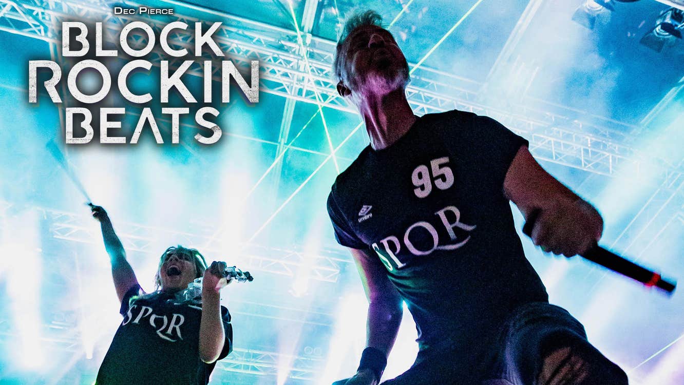 Dec Pierce Block Rockin Beats. 2 men in dark T-shirts on a stage with bright lights behind.