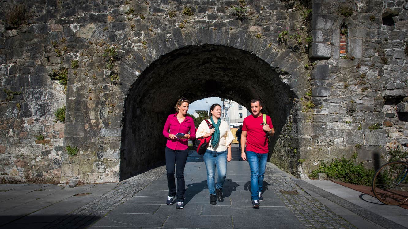 Friends walking through the Spanish Arch, Galway City