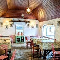 Rustic tea room interior with floral tablecloths and pastel chairs around small tables