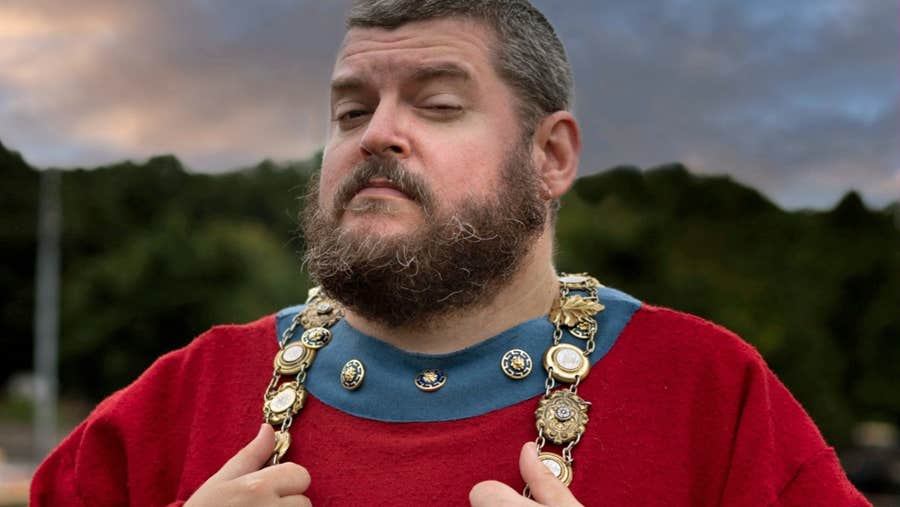 A tour guide in a red costume with decorative chain