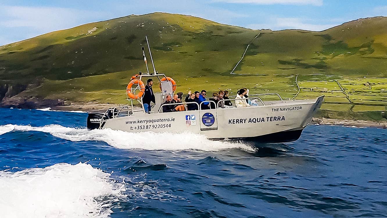 A speed boat with a group on board circle the island from the sea