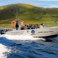 A speed boat with a group on board circle the island from the sea