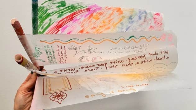 Silk Worm Families Drop-in: Ornamental Hangings - a hand holding a fan of drawings on thin white paper