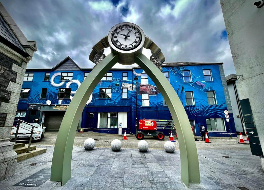 A modern sculpture featuring a clock supported by two metal posts