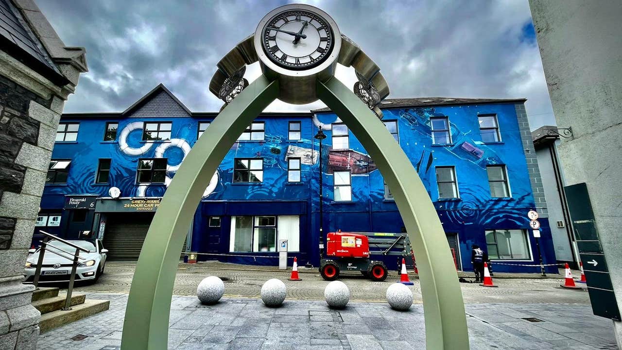 A modern sculpture featuring a clock supported by two metal posts