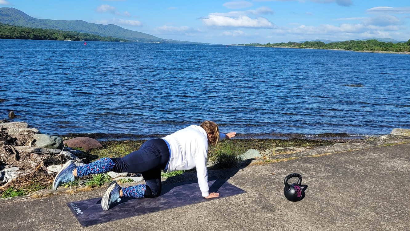 Person in a yoga pose on a pier next to the sea