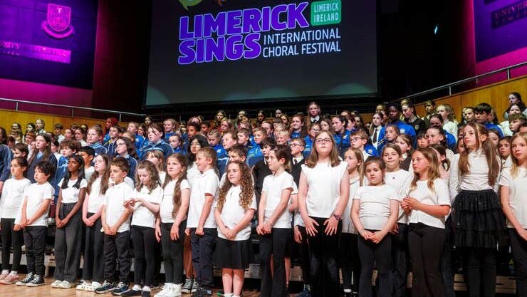 Large group of young children singing on a stage