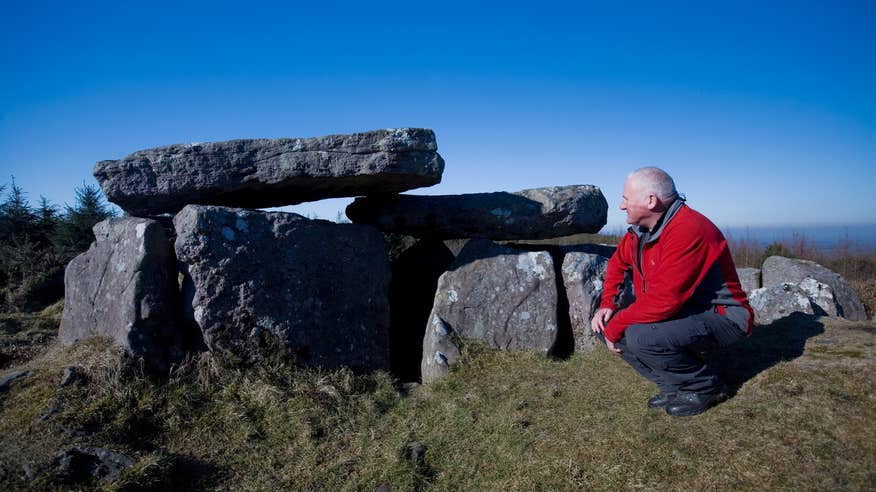 A man observing a dolmen in Glen of Aherlow in County Tipperary.