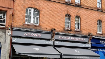 An exterior image of Adonis Flower Designers with plants on display outside the entrance door