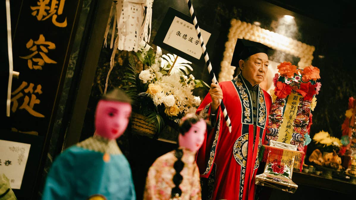 Film, The Last Dance, a man in ornate dress with flowers and blurred figures in the foreground.