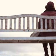 'An tÉalú' Ceoldráma Nua le Seán Óg Ó Duinnín - rear view of person in winter coat and hat seated at one end of a wooden bench.