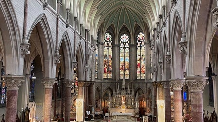 The interior of a church with a high vaulted ceiling and stained glass windows