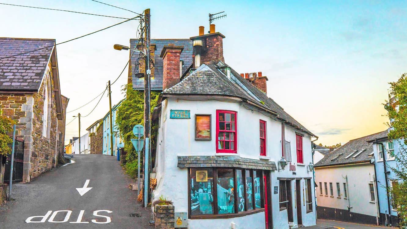 Historic Stroll in Old Kinsale view of an old corner shop painted white with red framed windows