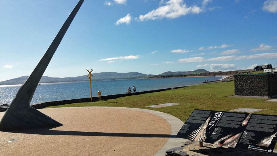 The Árthach Dána sculpture and sundial in Waterville with the bay in the background