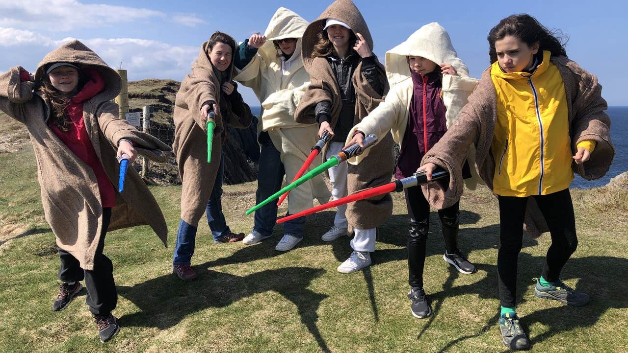 A family group in Star Wars costumes posed with light sabres