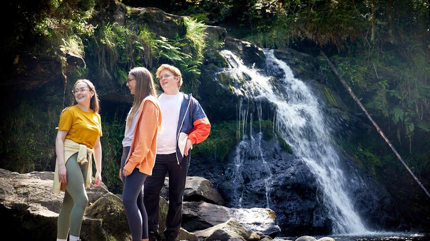 Friends standing beside a waterfall on the Glenbarrow Eco Walk.