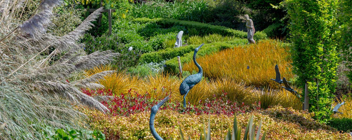 Statues of birds surrounded by shrubs and plants at the Arboretum Inspirational Gardens