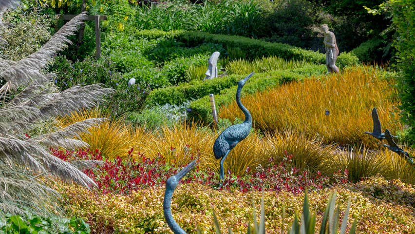 Statues of birds surrounded by shrubs and plants at the Arboretum Inspirational Gardens