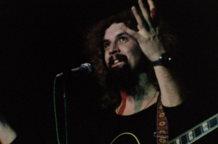 Billy Connolly with a guitar on stage.