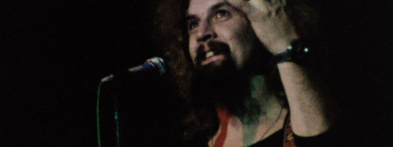 Billy Connolly with a guitar on stage.