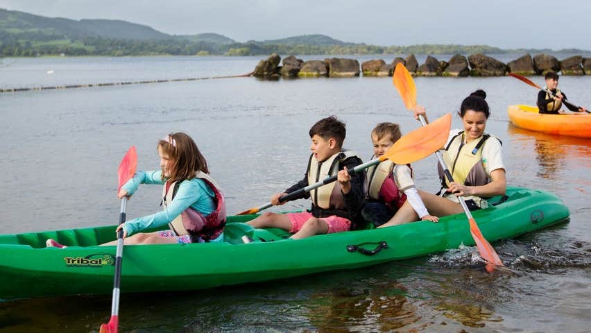 Three children and an adult kayaking on a lake