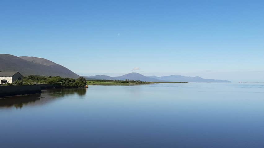 View of Blennerville Windmill overlooking the still waters of the harbour with mountains in the distance