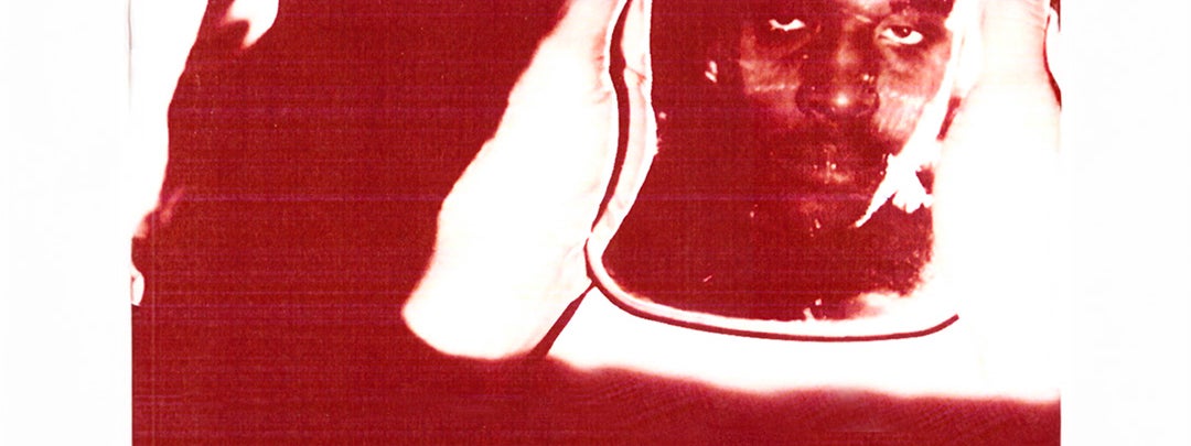 Dark red and white abstract image of to hands holding object with reflection of a man's face in.