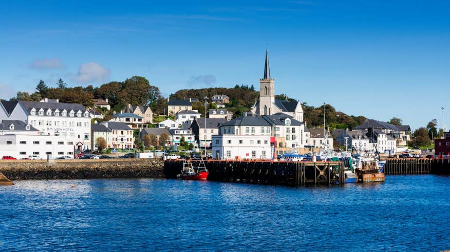 An image of boats by the pier in Killybegs against a backdrop of houses and a church