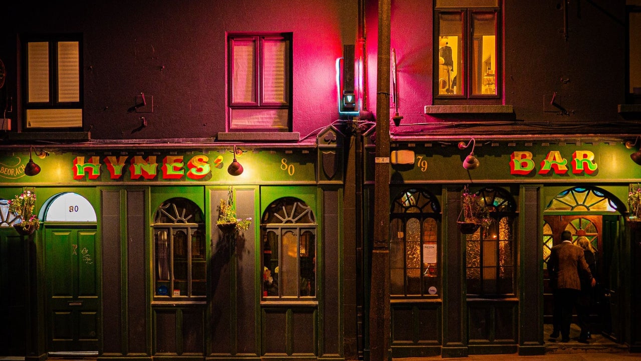 Exterior view of a bar illuminated at night with green frontage and traditional pub signage