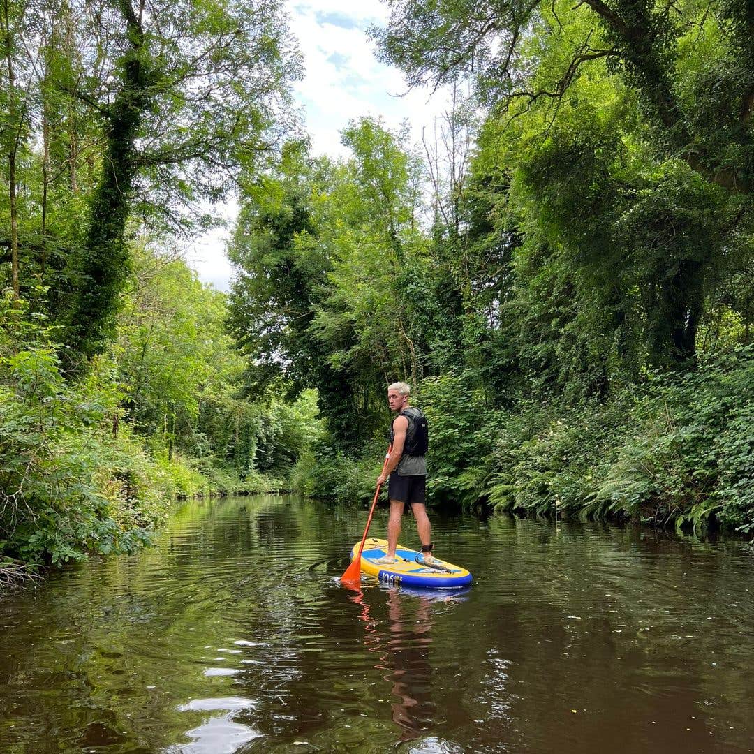 Man stand up paddleboarding on a river in Leitrim