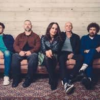 A group of 5 people sitting on a long sofa.