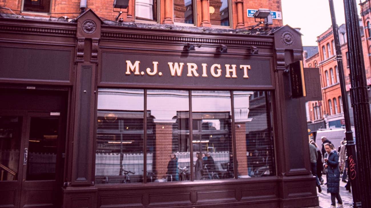Exterior of a pub on a city street with the family name above the window
