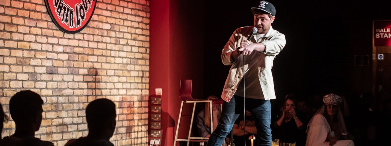 A man with a mic on a small stage pointing at an audience member