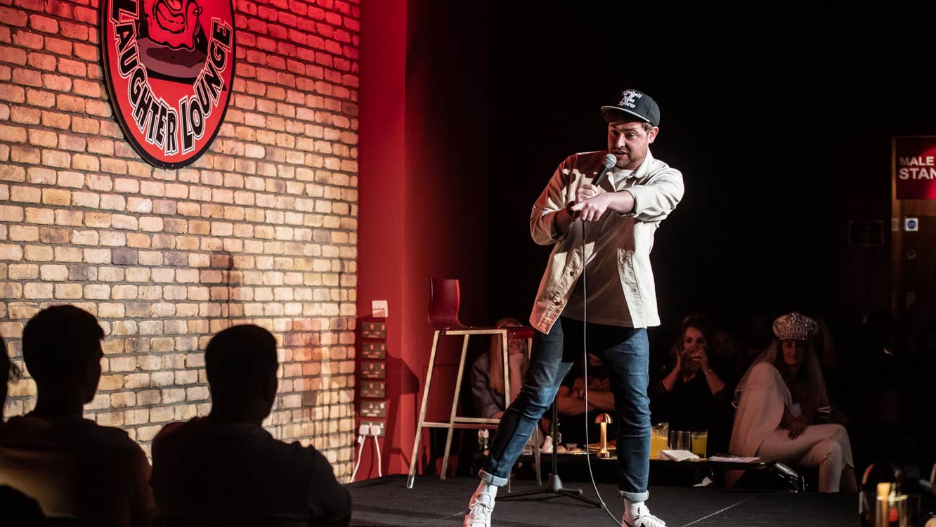 A man with a mic on a small stage pointing at an audience member