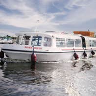 A white passenger boat named River Queen cruising on calm water