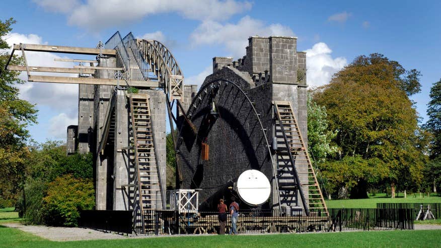 Two people standing in front The Great Telescope at Birr Castle Demesne, Offaly