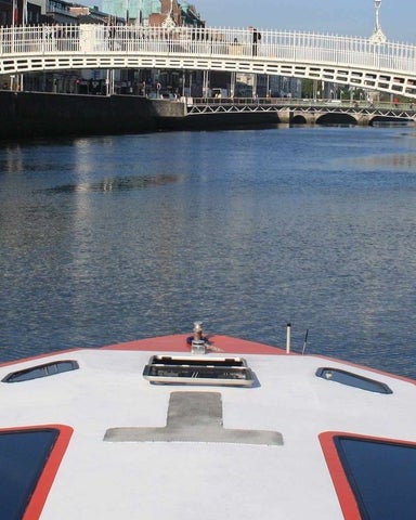 The boat cruising in the River Liffey approaching the Hapenny Bridge in Dublin City