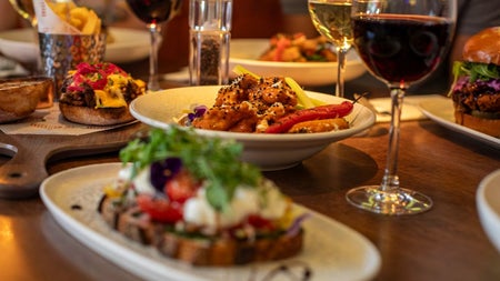 Different plates of food on a table with glasses of red and white wine