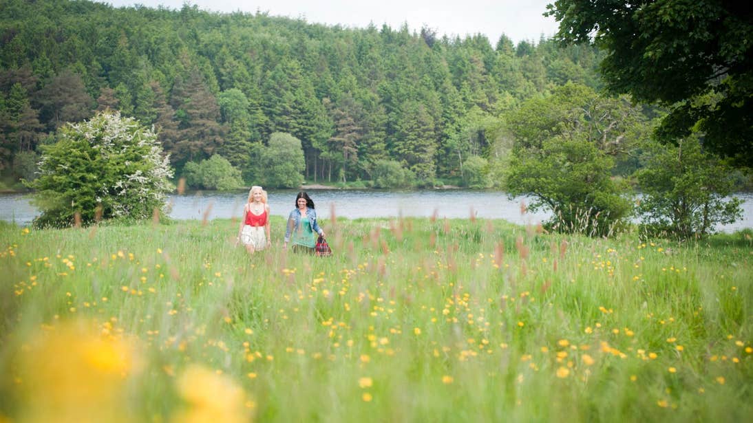 Two people walking through a meadow beside Lough Muckno in Monaghan