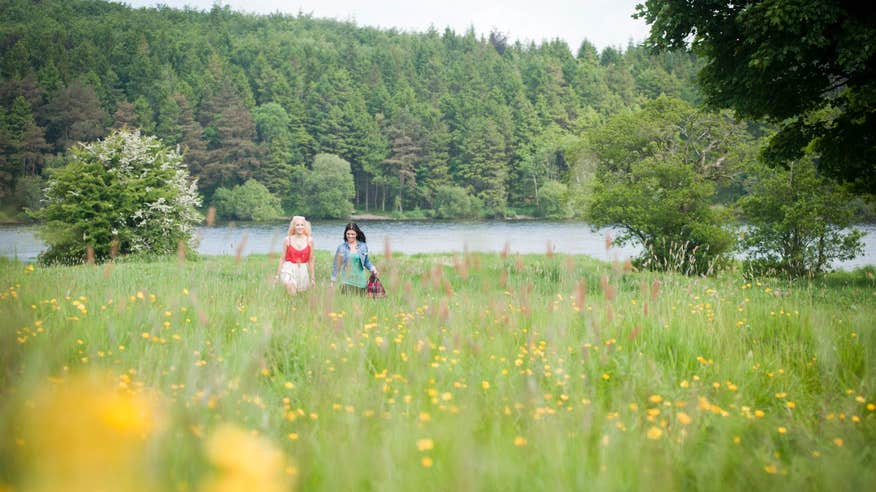 Two people walking through a meadow beside Lough Muckno in Monaghan