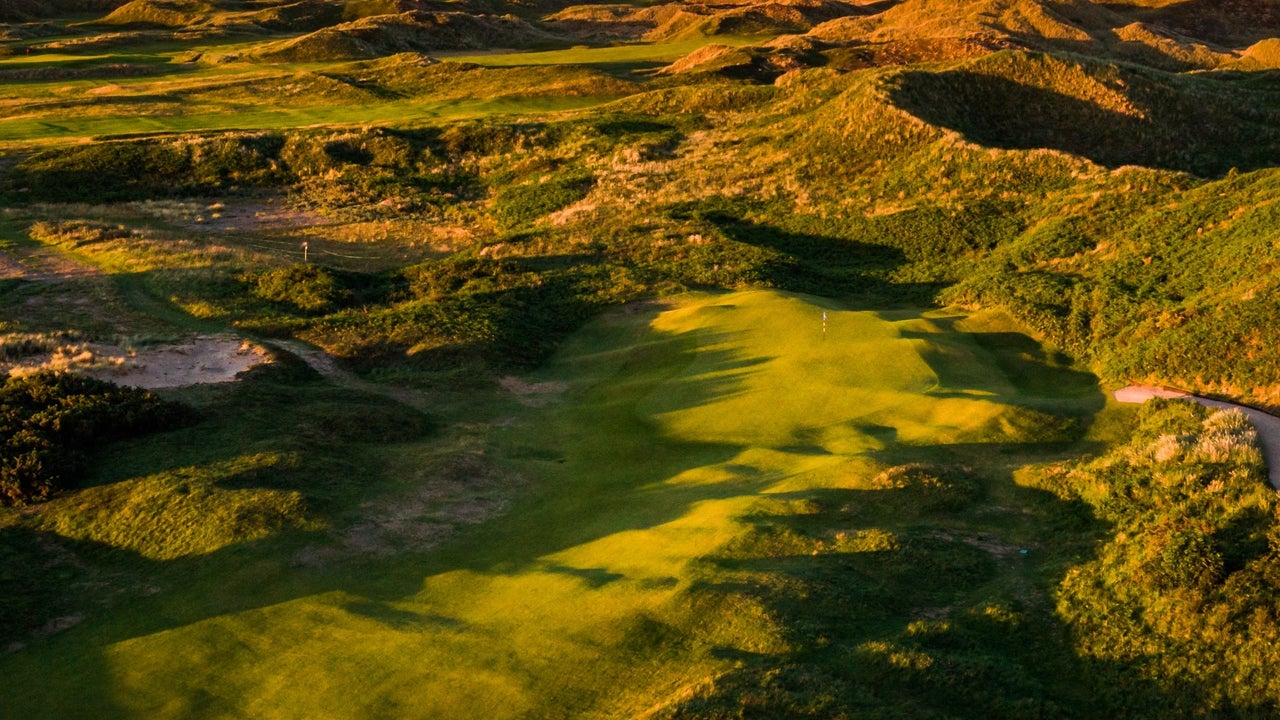 Aerial view of a golf green with the sea and an island in the background