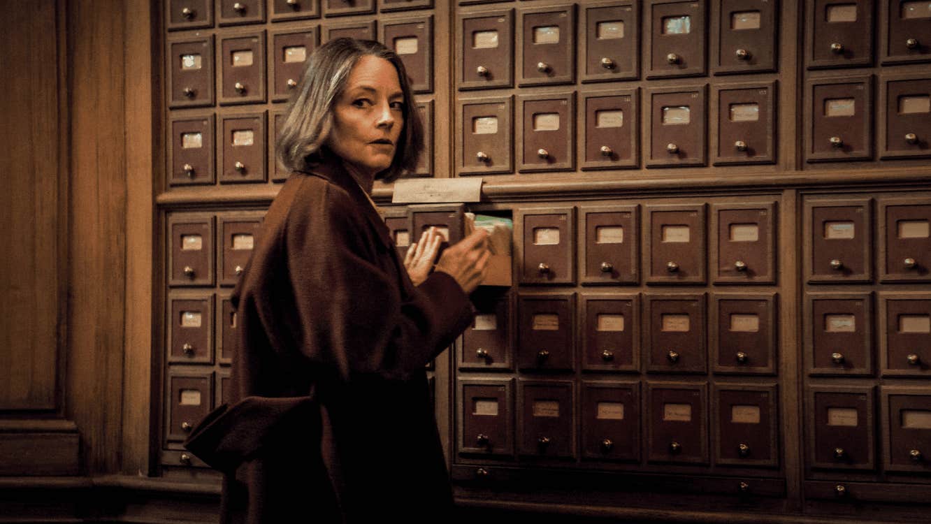 A woman looking over her shoulder while using a card catalogue.
