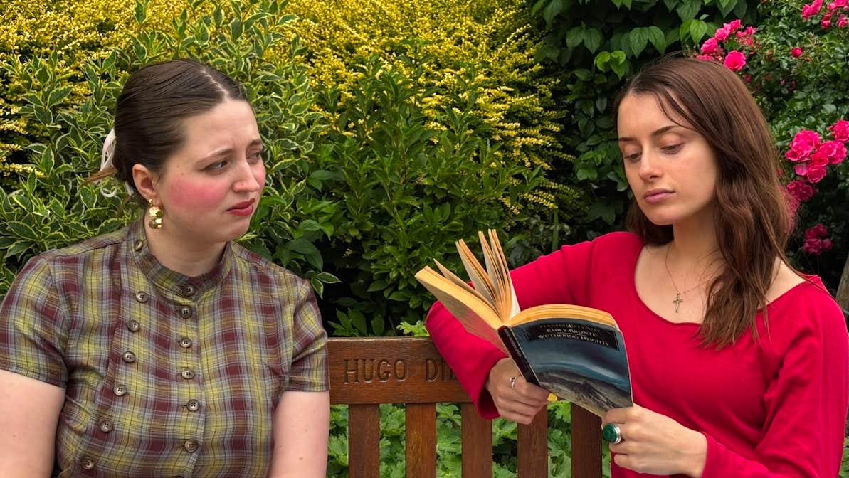 2 young women seated in a garden reading books